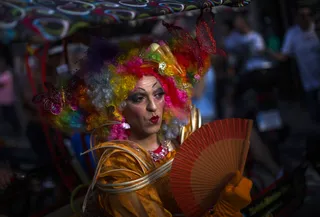Rainbows and Fans&nbsp; - A reveler pulled out their most festive wig and costume and strikes a pose for the annual gay pride march in Barcelona this past Saturday.&nbsp;(Photo: AP Photo/Emilio Morenatti)