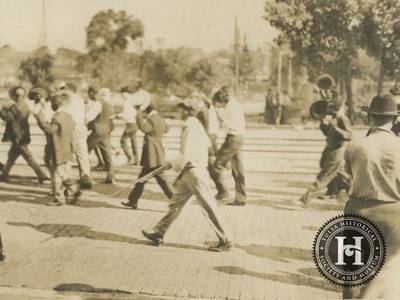 Detention - The Tulsa Race Massacre focused the racist anger of whites who lived in the area around Tulsa, Okla., on the prosperous Greenwood District and a mob treated the community like criminals. In this image a group of African American men being marched down a street toward a detention center.