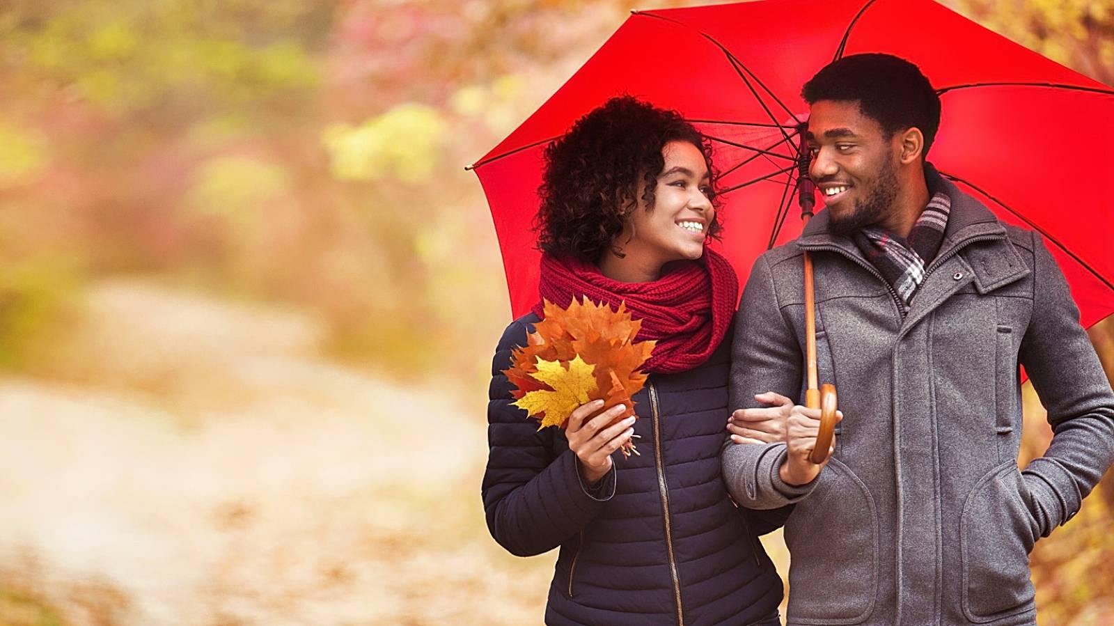 Young couple walking under umbrella at rainy autumn day - stock photo

