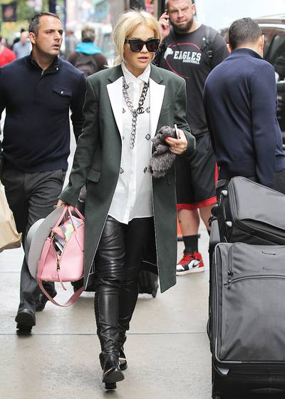 Casual Fab - Rita Ora checks out of her Soho hotel heads out in a long olive green coat, white button down blouse, black leather biker pants, a hate, shades and flats, accessorized with a classic Chanel chain.&nbsp;(Photo: Blayze / Splash News)