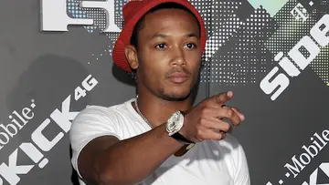 Romeo Miller with a red hat and white shirt, pointing.