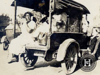 An Uncertain Future - As many as 10,000 people were displaced in the 1921 Tulsa Race Massacre. Many Black residents left Tulsa never to return, although an unknown number did stay and attempt to rebuid. This photo shows a small truck loaded with people and a woman sits with her legs dangling from the back.