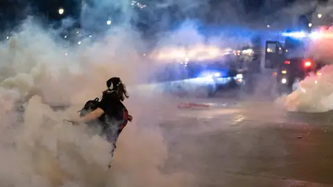 TOPSHOT - A protester hurls a tear gas canister back towards the Detroit police after tensions were sparked by arrests of protesters, through the streets of Detroit, Michigan for a second night May 30,2020 to protest the killing of George Floyd who was killed by a white officer who held his knee on his neck for several minutes. - Curfews were imposed on major US cities as clashes over police brutality erupted across America with demonstrators ignoring warnings from President Donald Trump that his government would stop the violent protests "cold." (Photo by SETH HERALD / AFP) (Photo by SETH HERALD/AFP via Getty Images)