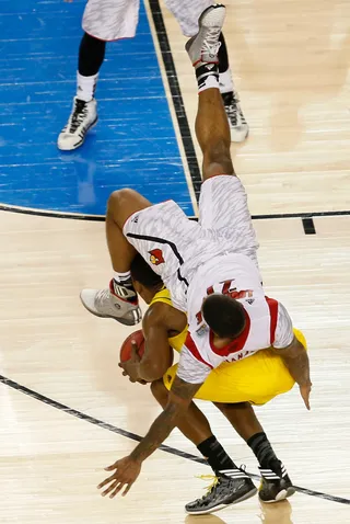 Oof! - Cardinals' Behanan took a tumble over Michigan's Glenn Robinson III. &nbsp;(Photo: Kevin C. Cox/Getty Images)