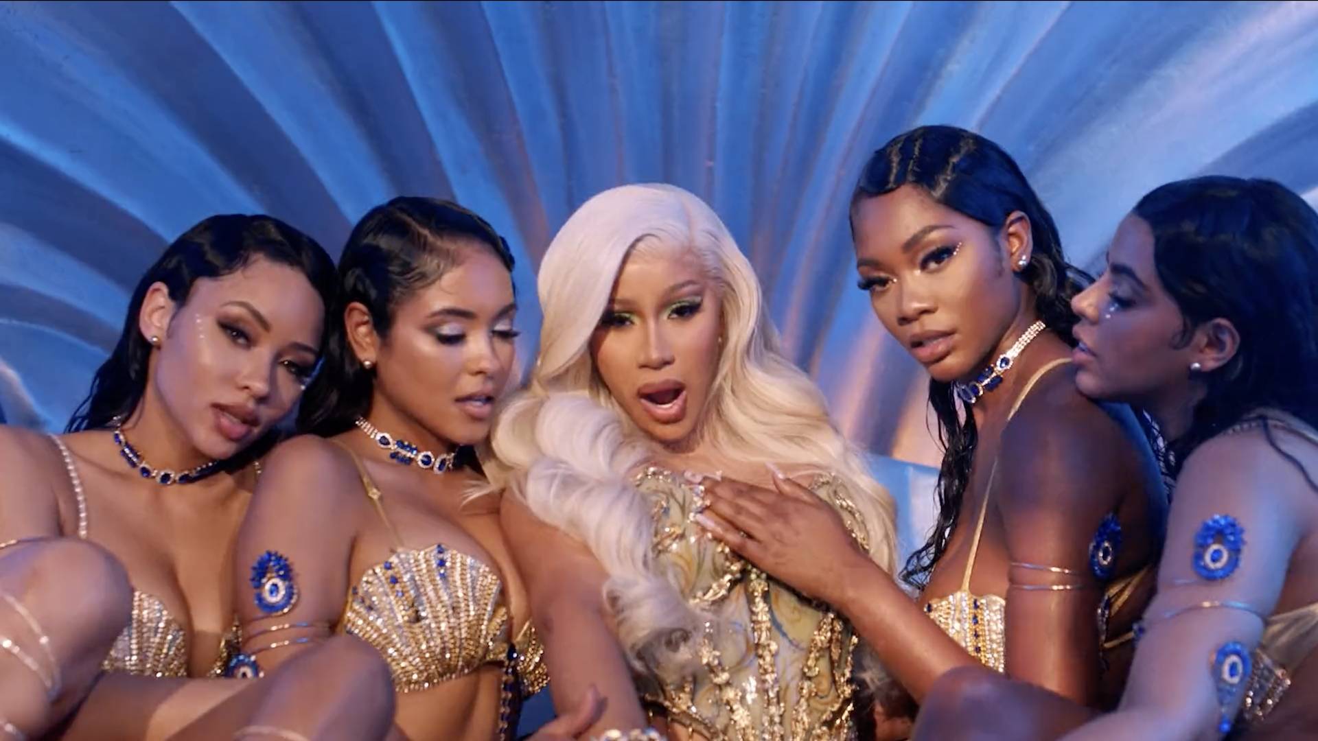 Cardi B wearing a gold dress with her back up dancers.