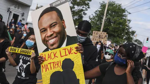 REVERE, MA - JUNE 9: A demonstrator holds a sign for Botham Jean while marching during a demonstration on June 9, 2020 in Revere, MA for George Floyd and other Black Americans killed at the hands of law enforcement. The peaceful march was been planned by Black and Brown Youth, a group based in Revere, who have come together to form Black Lives Matter Revere. (Photo by Erin Clark/The Boston Globe via Getty Images)