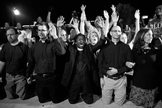 Praying for Justice - Reverend Osagyefo Uhuru Sekou kneels with fellow clergy members in the driveway of the Ferguson police department in a show of solidarity with protesters.&nbsp;(Photo: Lucas Alvarado-Farrar/Whose Streets Media)