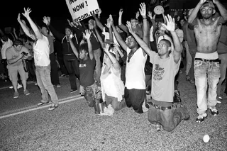 Not Backing Down - Protesters kneel in the street with their hands raised as they are approached by oncoming police vehicles outside the Ferguson Police Department.&nbsp;(Photo: Lucas Alvarado-Farrar/Whose Streets Media)