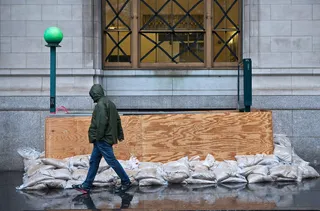 Shoring Up the Subways - A man walks past a barricaded subway entrance near Battery Park Monday. The core of Sandy's force is supposed to hit the New York area Monday night.(Photo:&nbsp; Andrew Burton/Getty Images)