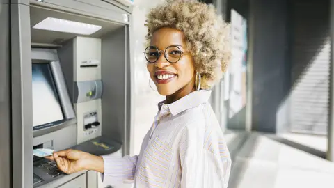 Afro-Latina woman with afro hair, withdrawing money from the ATM.