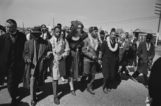 Marching with Dr. Martin Luther King Jr. - John Lewis marching arm in arm with Dr. Martin Luther King Jr., Reverend Ralph Abernathy, Ralph Bunche, Abraham Joshua Heschel, Fred Shuttlesworth, and more during a march in Selma, Alabama on March 21, 1965.