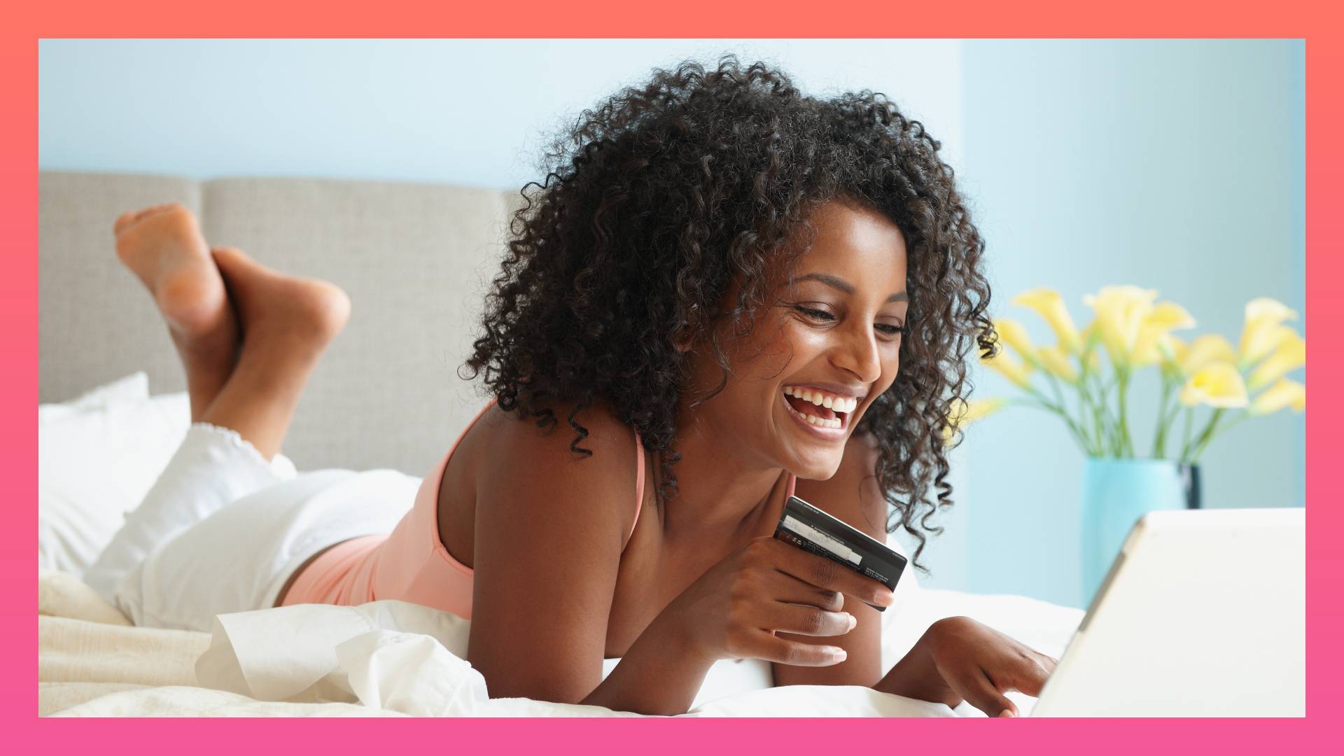 Black woman in bed shopping online with credit card 