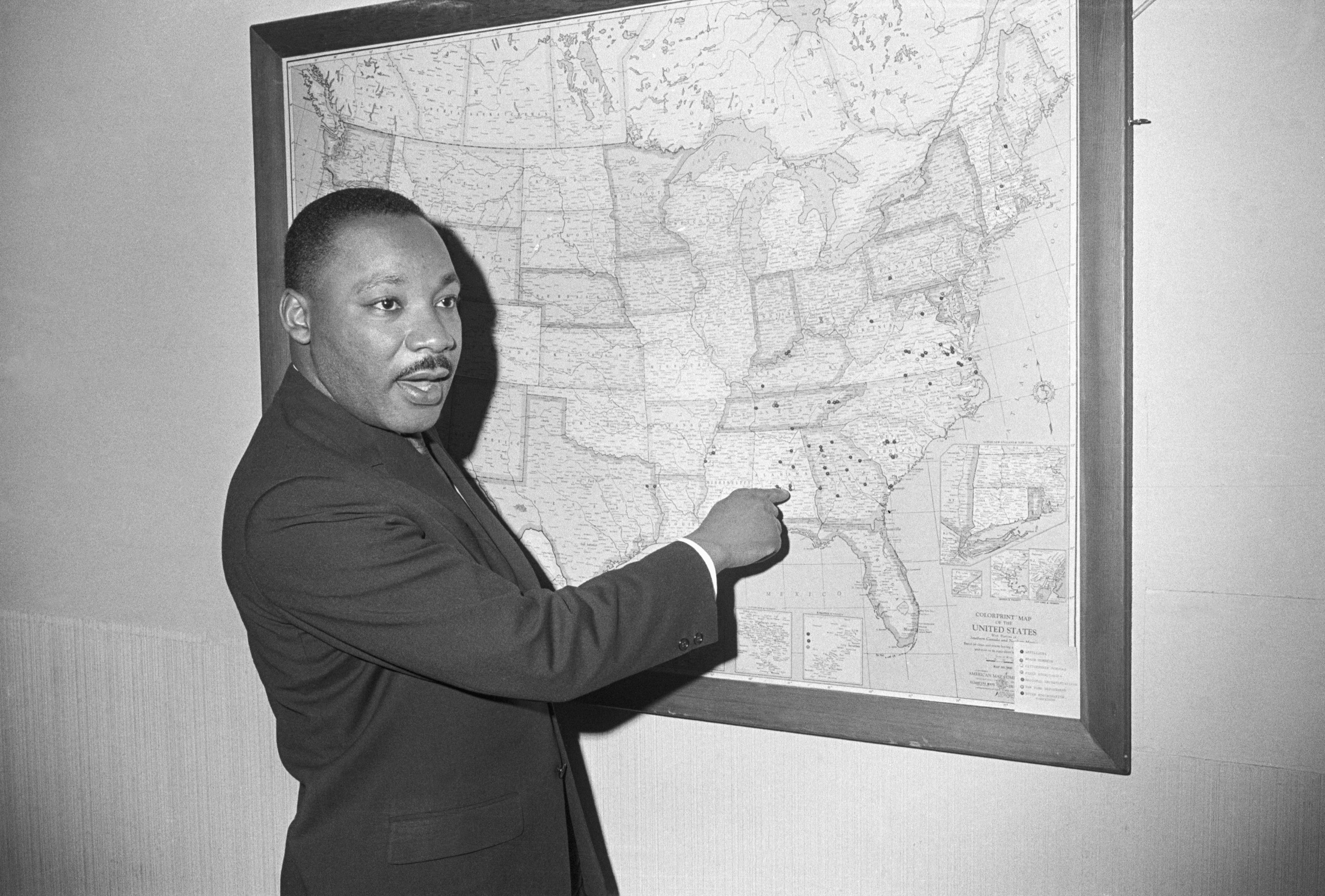 (Original Caption) 1/15/1965-Atlanta, GA: Dr. Martin Luther King points to Selma, Alabama on a map at a Southern Christian Leadership Conference office, as he calls for a three-pronged attack on racial barriers. Negro leaders indicate that January 18 will bring the biggest organized test to date of the new Civil Rights law. Volunteers are scheduled to march on the voter registration office, while others, too young to vote, will test the public accomodations section of the act. Still others will seek employment.