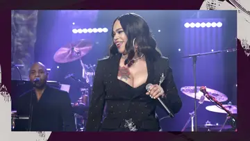 Faith Evans singing in a black dress, against a purple background.