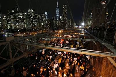 #NeverForget - On the second night of protests, protesters carry a collection of mock coffins bearing the names of victims of fatal police encounters as they cross the eastbound traffic lanes of the Brooklyn Bridge.&nbsp;(Photo: AP Photo/Jason DeCrow)
