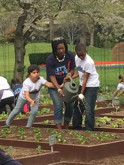 Until the April Showers ... -  A Let's Move! volunteer helps students water a flat of seedlings.(Photo: Joyce Jones/BET)