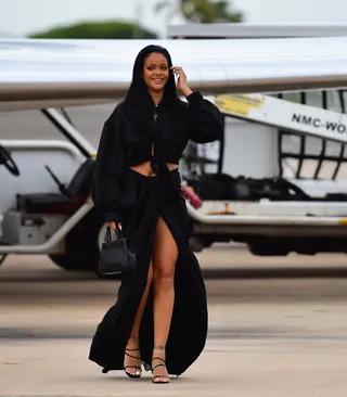 Barbados Baddie - Rihanna always looks fly but her summertime 'fits are on another level! Every summer we look forward to Rihanna's Crop Over 'fits in Barbados and this year was no different. The multifaceted mogul touched down on her island hom wearing a Collina Strada black, satin, crop top ($295) paired with her extra long, draped Fenty skirt ($840). She finished off the all-black look with a pair of strappy heels and her favorite Maison Alaïa mini tote. (Photo: Mega Agency)