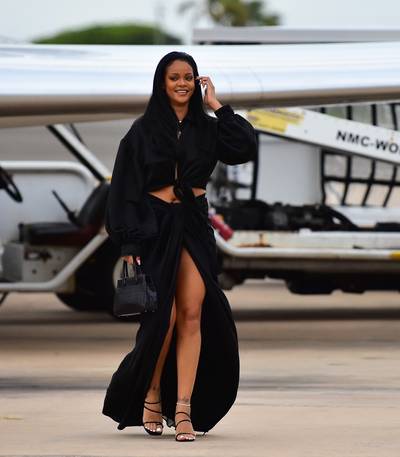 Barbados Baddie - Rihanna always looks fly but her summertime 'fits are on another level! Every summer we look forward to Rihanna's Crop Over 'fits in Barbados and this year was no different. The multifaceted mogul touched down on her island hom wearing a Collina Strada black, satin, crop top ($295) paired with her extra long, draped Fenty skirt ($840). She finished off the all-black look with a pair of strappy heels and her favorite Maison Alaïa mini tote. (Photo: Mega Agency)