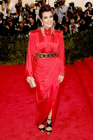 Kris Jenner - Mama Jenner brings the edge in a fiery red gown detailed with sumptuous draping and cinched with a gold-and-black belt. Swingy tasseled gold earrings let us know that she’s here to win.  (Photo: Dimitrios Kambouris/Getty Images)