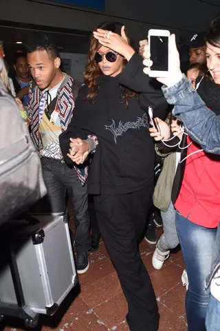 Fashion Fandemonium - Rihanna shields herself from the flashing lights as fans flock to see her upon her arrival at Charles de Gaulle airport in Paris for Fashion Week.(Photo: Neil Warner / Splash News)