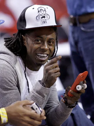 Feel the Heat\r - Lil Wayne has a laugh while texting courtside at the Miami Heat vs.&nbsp;New York Knicks Game 1 of the NBA Eastern Conference basketball playoffs in Miami. Check Weezy's cellphone case — a mini skateboard to go along with a baseball cap from his Truk Fit clothing line. \r\r\r(Photo: REUTERS/Andrew Innerarity)