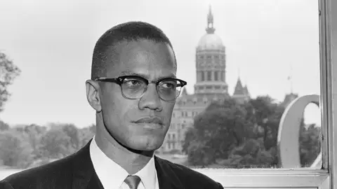 (Original Caption) 6/4/1963-Hartford, CT: Malcolm X, leading spokesman for the Black Muslim movement, is shown with the dome of the Connecticut Capitol behind him as he arrived in Hartford for a two day visit.