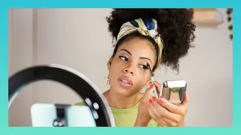 Female influencer giving make-up tutorial through vlogging at home