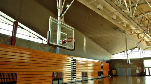 Empty high school gym with basketball hoop and bleachers