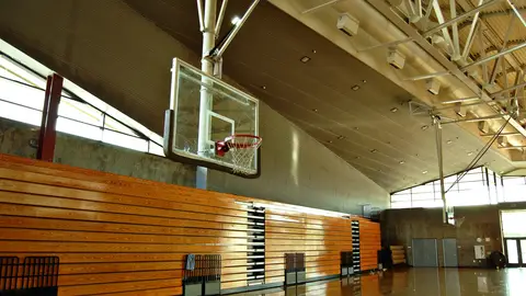 Empty high school gym with basketball hoop and bleachers