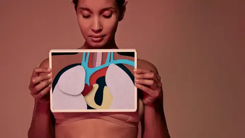 Female holding tablet in front of body to display coloured x-ray illustrations made out of hand made paper structures