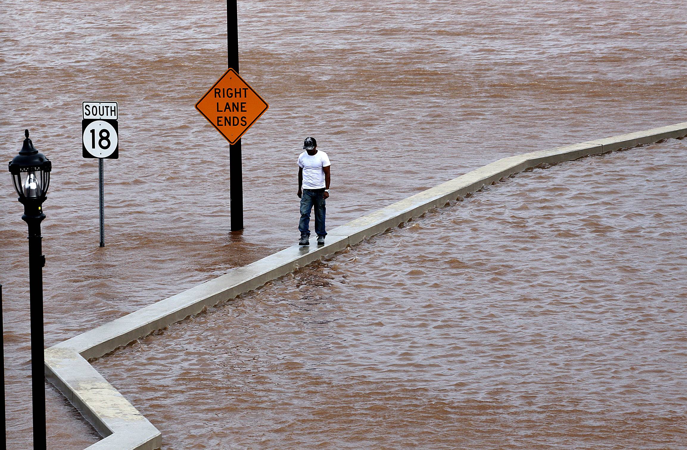 Irene Floods Highways  - A man walks on top of a wall next to a flooded highway in New Brunswick, New Jersey on Aug. 28, 2011, as heavy rains left by Hurricane Irene cause inland flooding of rivers and streams. Flood waters rose all across New Jersey on Sunday, closing roads from side streets to major highways as Hurricane Irene weakened and moved on, leaving 600,000 homes and businesses without power.(Photo: AP Photo/Mel Evans)