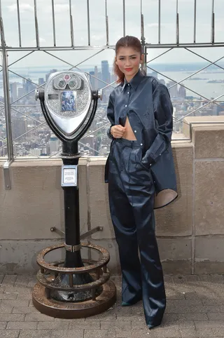Zendaya Lights Up the Empire State - Looking fly in the concrete jungle! Zendaya wore a sleek, midnight blue,&nbsp;FW19 Peter Do bonded, satin pantsuit with the bottom buttons of the blouse unbuttoned while promoting her upcoming film at the Empire State Building.&nbsp;