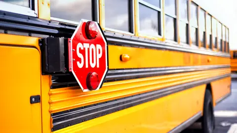 Close up of a yellow school bus with the red STOP sign