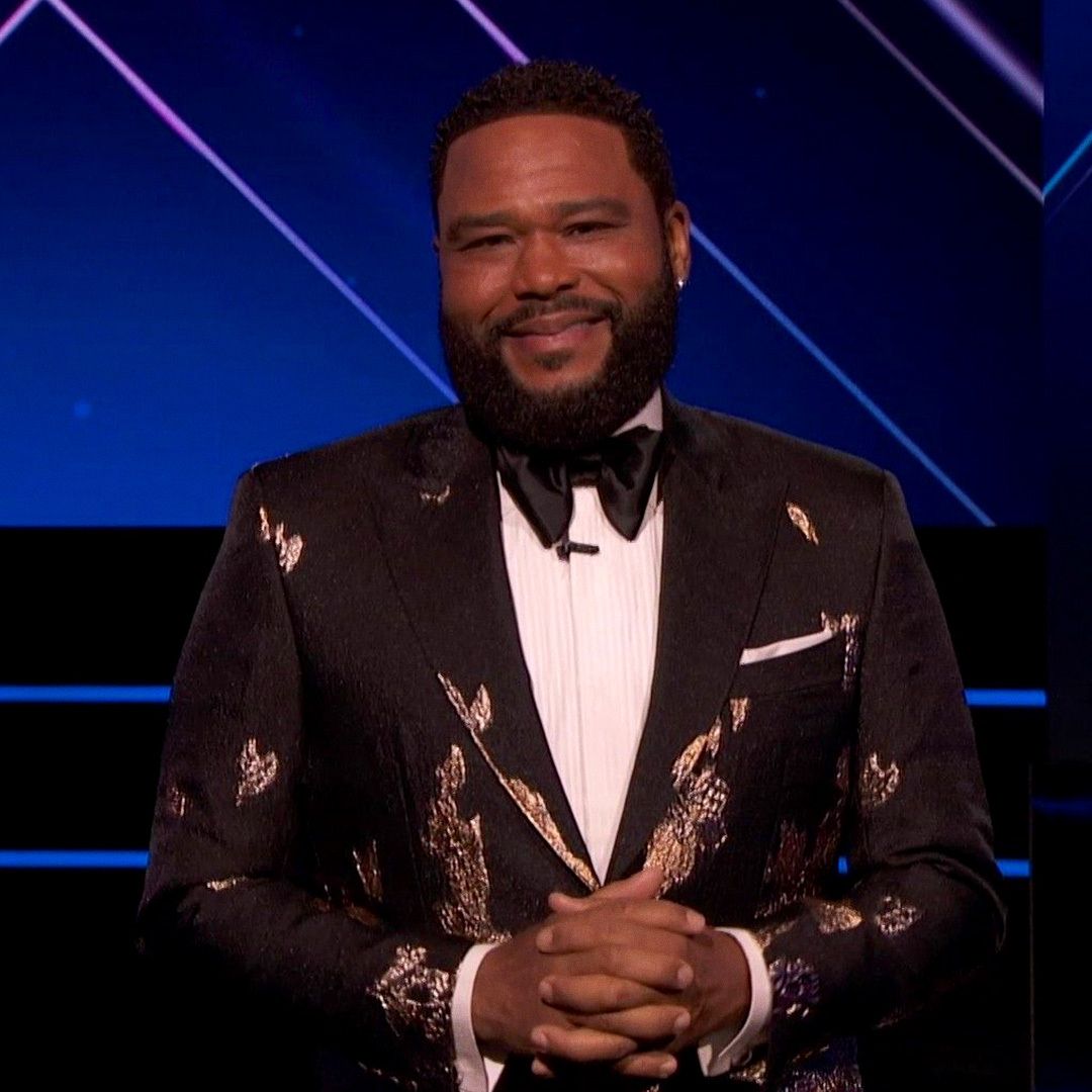 Anthony Anderson hosts the 53rd NAACP Image Awards in a black and gold tuxedo against a blue background.