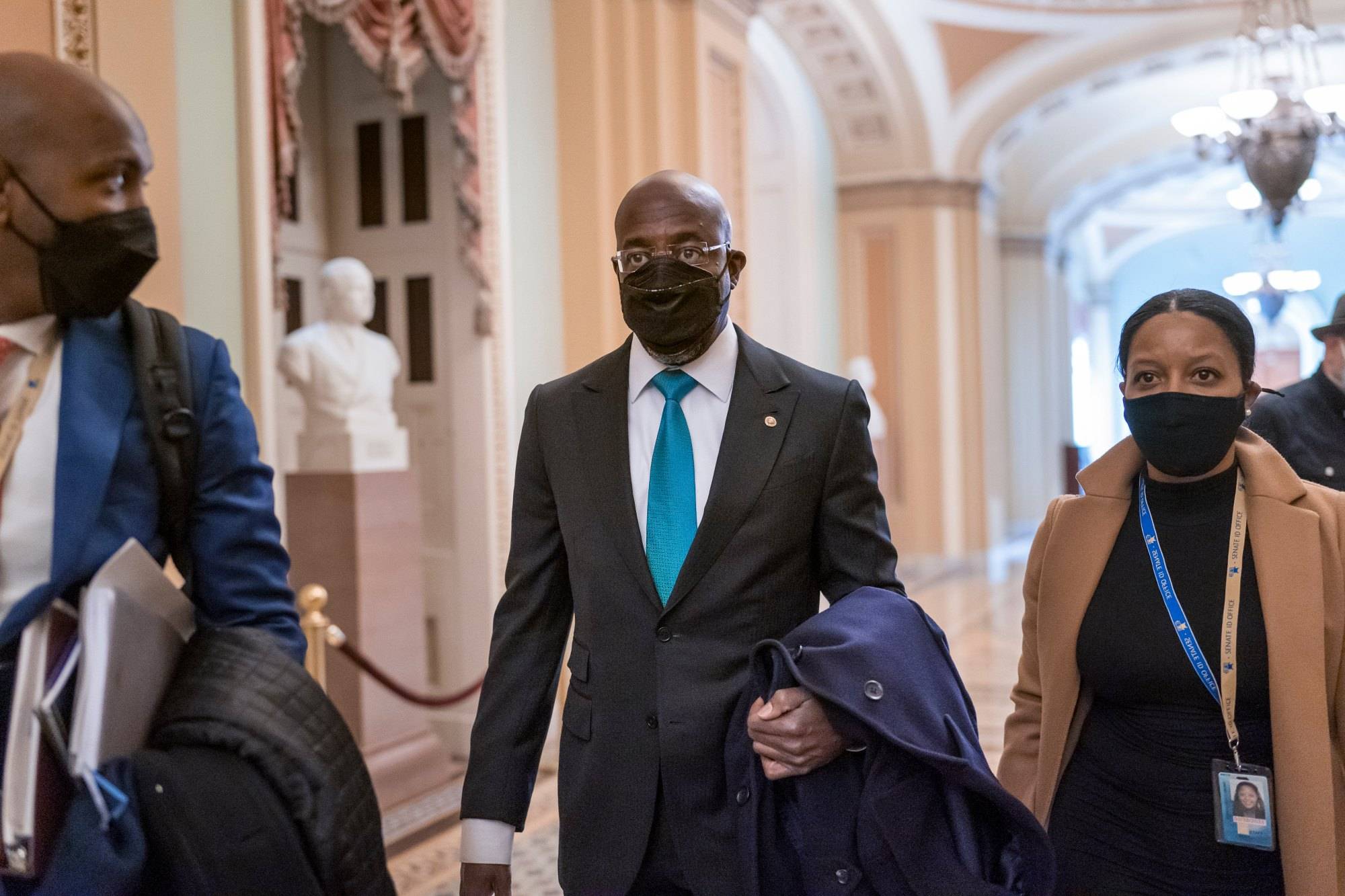 Newly-elected Sen. Raphael Warnock, D-Ga., center, leaves a meeting with other members of the Democratic Caucus on their their first full day in the majority, at the Capitol in Washington, Thursday, Jan. 21, 2021. Warnock, the senior pastor of Ebenezer Baptist Church in Atlanta, unseated Republican Sen. Kelly Loeffler of Georgia.  (AP Photo/J. Scott Applewhite)