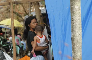 Woman Holds Her Child Close - A woman looks over as she holds a young child at a makeshift shelter. Many survivors continue to look for missing family members following the catastrophic events.(Photo: AP Photo/Wally Santana)