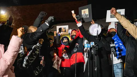 The crowd raises their fists around Hill's daughter Karissa Hill, and nephew Terry Fagain at a press conference and candlelight vigil for Andre Hill outside the Brentnell Community Recreation Center in Columbus, Ohio on December 26, 2020. - The fatal shooting of an unarmed Black man by police in  Columbus, Ohio -- the US city's second such killing this month -- sparked a fresh wave of protests on December 24 against racial injustice and police brutality in the country. Andre Maurice Hill, 47, was in the garage of a house on the night of December 21 when he was shot several times by a police officer who had been called to the scene for a minor incident. (Photo by STEPHEN ZENNER / AFP) (Photo by STEPHEN ZENNER/AFP via Getty Images)