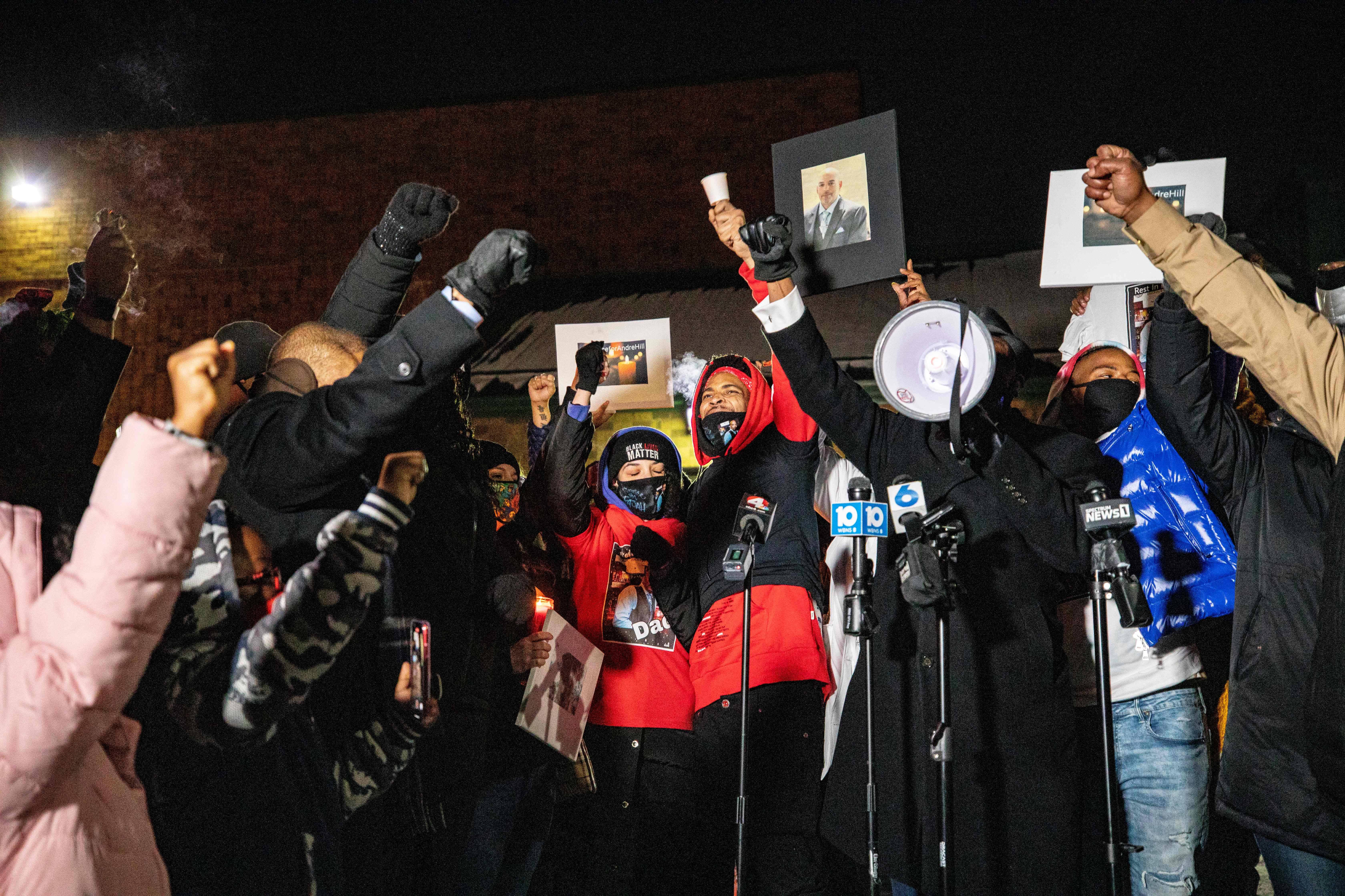 The crowd raises their fists around Hill's daughter Karissa Hill, and nephew Terry Fagain at a press conference and candlelight vigil for Andre Hill outside the Brentnell Community Recreation Center in Columbus, Ohio on December 26, 2020. - The fatal shooting of an unarmed Black man by police in  Columbus, Ohio -- the US city's second such killing this month -- sparked a fresh wave of protests on December 24 against racial injustice and police brutality in the country. Andre Maurice Hill, 47, was in the garage of a house on the night of December 21 when he was shot several times by a police officer who had been called to the scene for a minor incident. (Photo by STEPHEN ZENNER / AFP) (Photo by STEPHEN ZENNER/AFP via Getty Images)