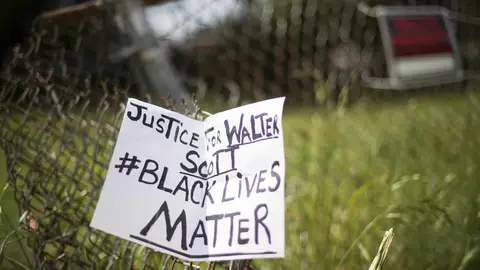A placard is tied to a fence outside the vacant lot where Walter Scott, the 50-year-old man who was fired at eight times was killed as he ran away from an officer after a traffic stop in North Charleston, South Carolina on April 8, 2015. Police officer Michael Slager,33, who fatally shot Scott in the US city of North Charleston has been fired after he was charged with murder, the mayor said. Speaking at a highly charged press conference frequently interrupted by residents angered at America's latest high-profile police killing of a black man, Mayor Keith Summey said the city had moved quickly to fire the officer after Saturday's shooting.   AFP PHOTO/JIM WATSON        (Photo credit should read JIM WATSON/AFP via Getty Images)