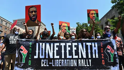 Protestors hold pictures of George Floyd as they march during a Juneteenth rally at Grand Army Plaza on June 19, 2020 in the Brooklyn Borough of New York City. - The US marks the end of slavery by celebrating Juneteenth, with the annual unofficial holiday taking on renewed significance as millions of Americans confront the nation's living legacy of racial injustice. (Photo by Angela Weiss / AFP) (Photo by ANGELA WEISS/AFP via Getty Images)