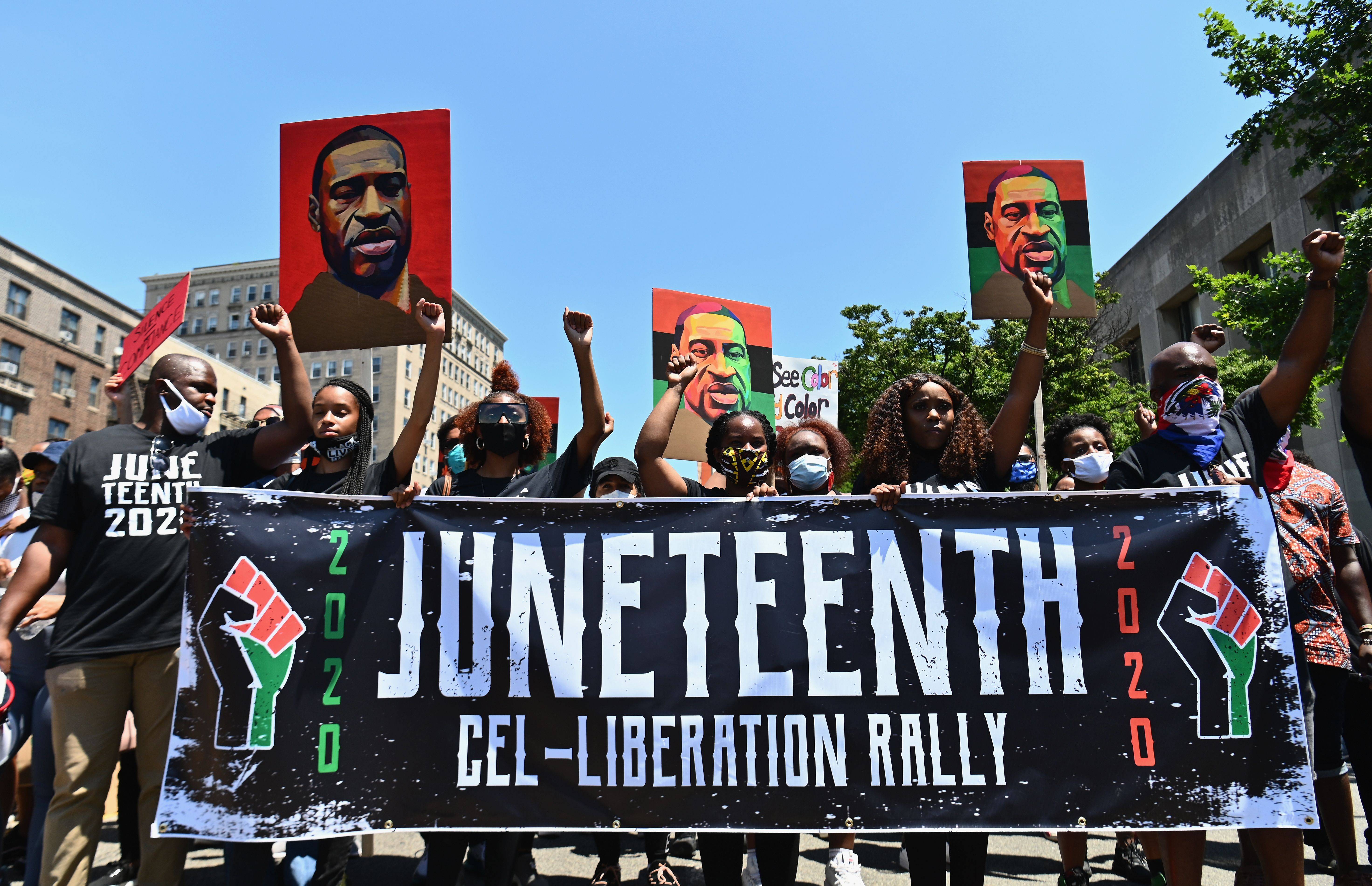 Protestors hold pictures of George Floyd as they march during a Juneteenth rally at Grand Army Plaza on June 19, 2020 in the Brooklyn Borough of New York City. - The US marks the end of slavery by celebrating Juneteenth, with the annual unofficial holiday taking on renewed significance as millions of Americans confront the nation's living legacy of racial injustice. (Photo by Angela Weiss / AFP) (Photo by ANGELA WEISS/AFP via Getty Images)