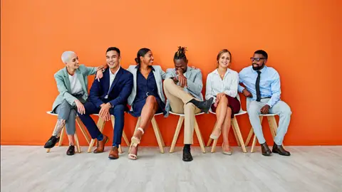 Shot of a group of young adult businesspeople sitting against an orange background - stock photo
