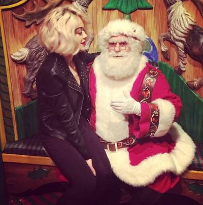 Rita Ora  - Perched on Santa’s lap, Rita writes, “The moment he realized I'm being Naughty. But he liked it!”   (Photo: Rita Ora via Instagram)