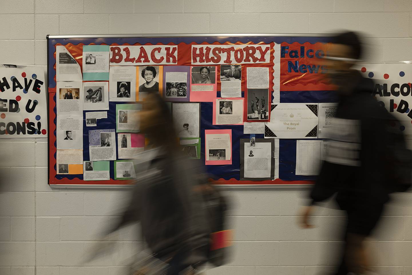 people walking by a bulletin board