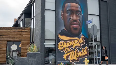 LOS ANGELES, CALIFORNIA - APRIL 21: A woman without a mask walks past a mural of George Floyd that reads, "changed the world" amid the coronavirus pandemic on April 21, 2021 in Los Angeles, California. Los Angeles County moved into Covid-19 orange tier restrictions on April 5 allowing increased capacity at restaurants, movie theaters and museums. (Photo by Alexi Rosenfeld/Getty Images)