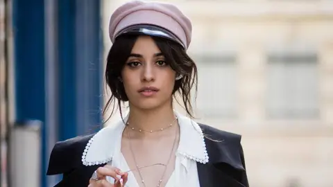 Singer Camila Cabello wearing a white Bluemarine overall Gianvito Rossi pumps, pink military hat Ruslan Baginskiy seen on October 16, 2017 in Paris, France