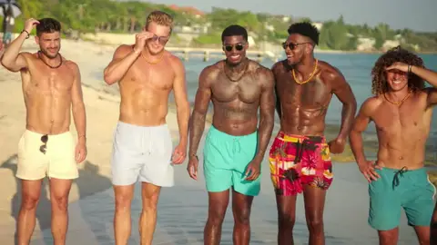 Five shirtless men standing on beach in 'Fboy Island', New HBO Max Reality Dating Show