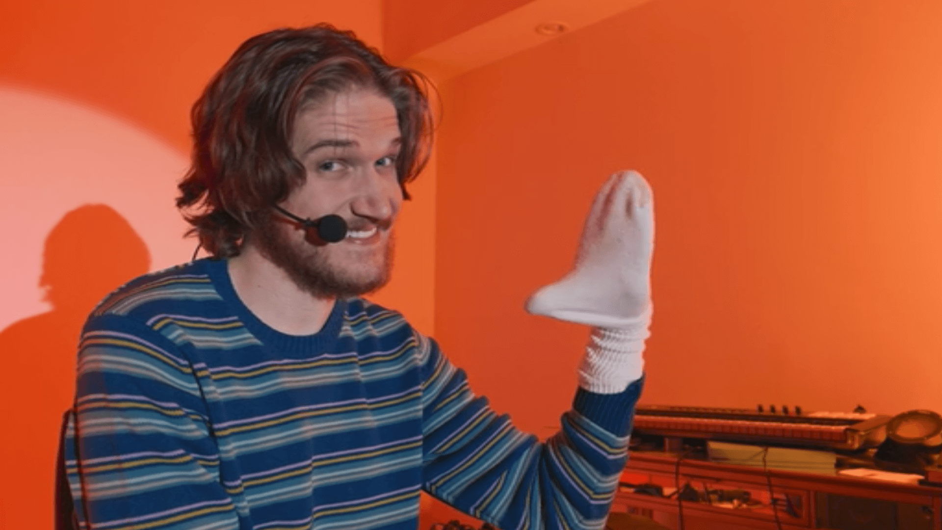 Bo Burnham Sock puppet in blue jumper and smile Inside on Netflix orange background