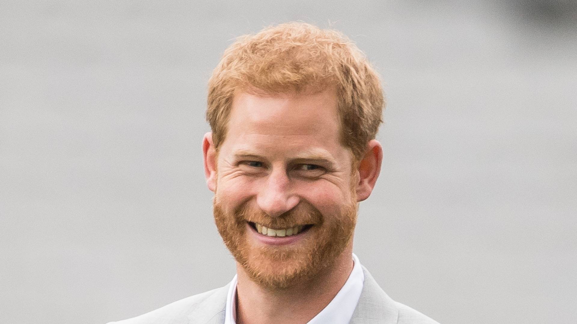 Prince harry smiling in front of grey background