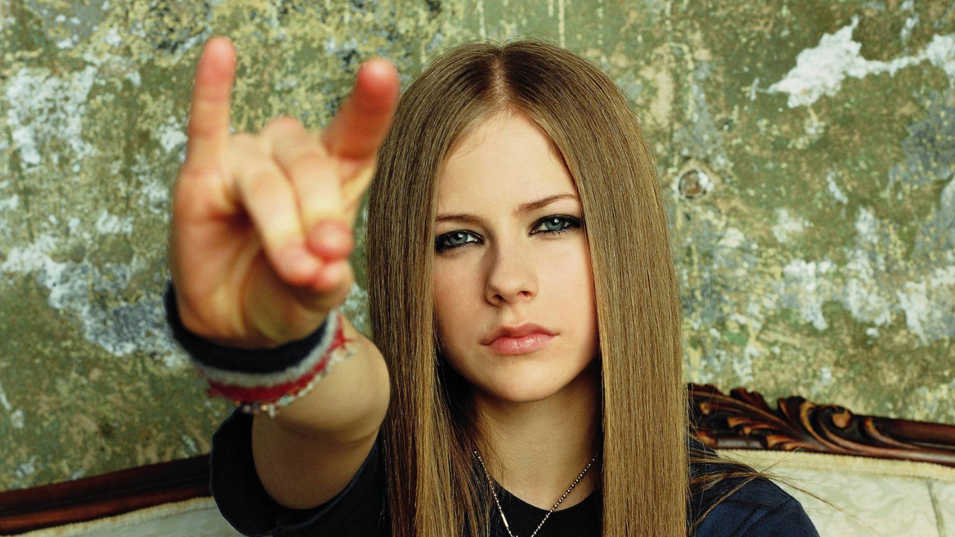Teenage Avril Lavigne in early 2000s looking to camera and making hand gesture 